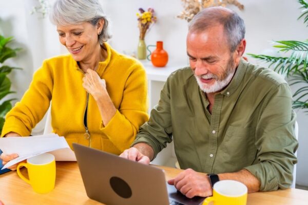 Happy senior couple working on personal financial bills at home