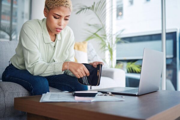 Home finance and woman with a laptop stress and calculator with budget planning review finances and inflation Person paperwork and girl on a sofa pc or counting with wallet and bankruptcy