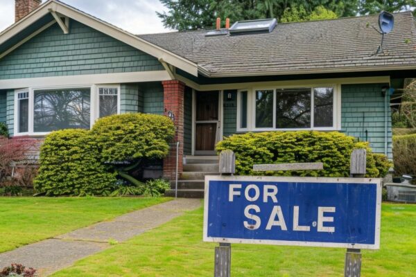 Home for sale with a sign with written FOR SALE in front of a house real estate sales concept