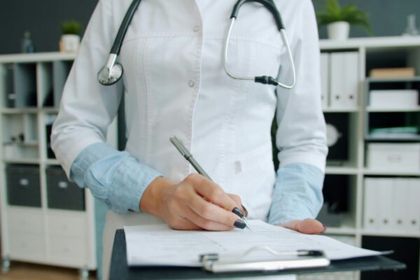 Doctor writing on clipboard in office