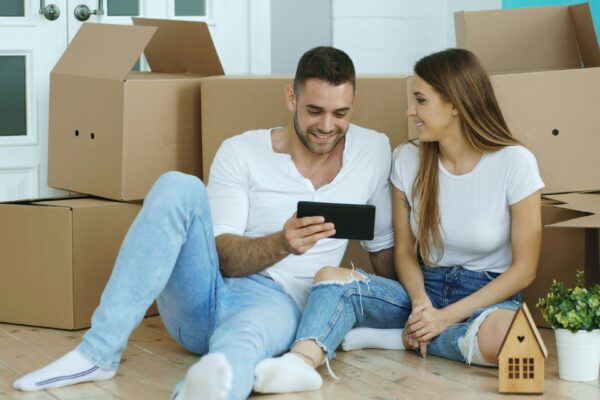 Couple looking at tablet surrounded by moving boxes