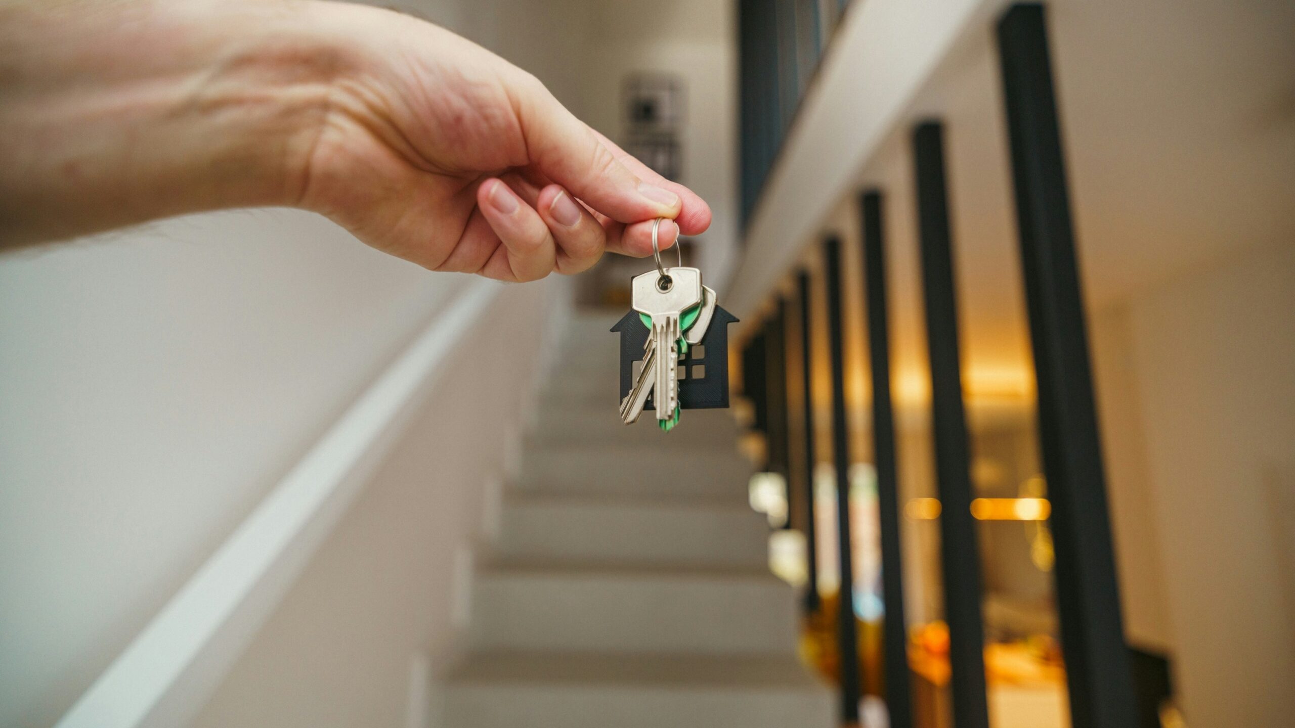 Here's a possible caption: keys being held in front of a staircase.