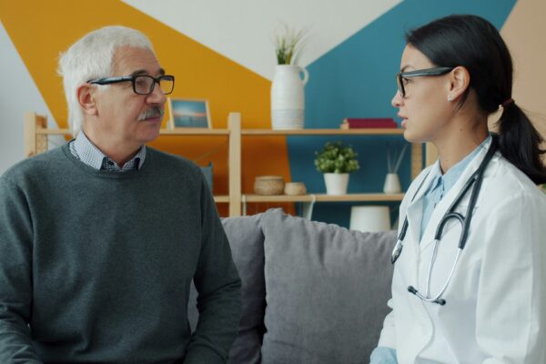 Doctor consults with an elderly patient on a couch.