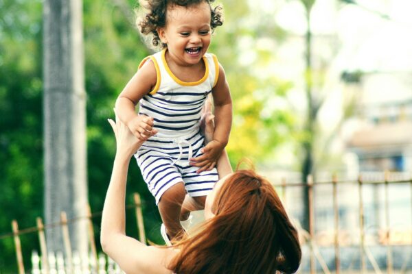 selective focus photo of woman lifting child during daytime
