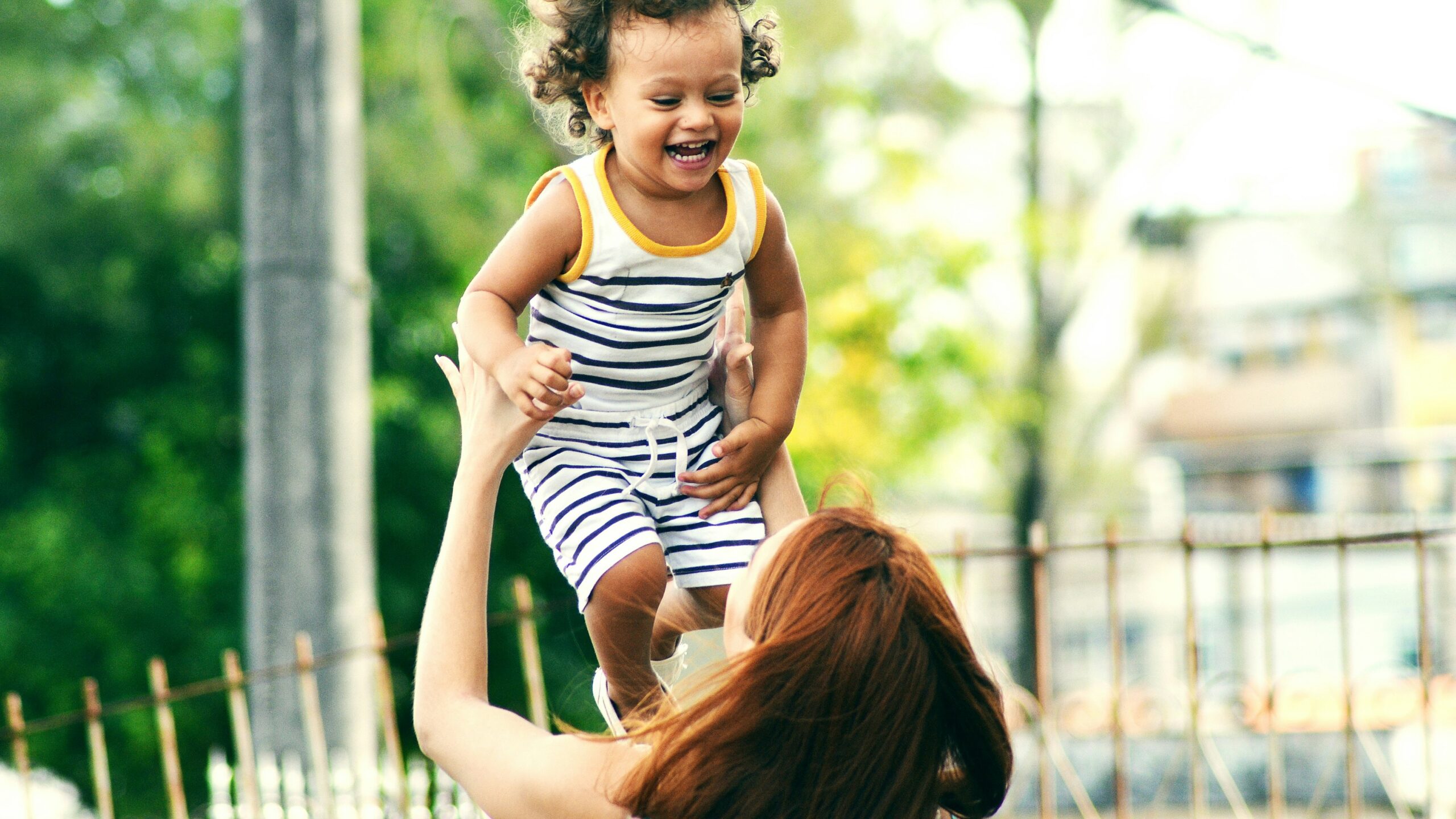 selective focus photo of woman lifting child during daytime