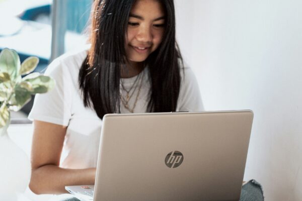 woman in white shirt using laptop