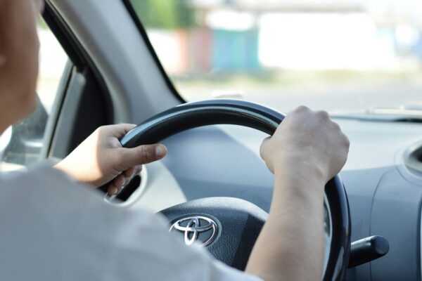 person in white long sleeve shirt driving car