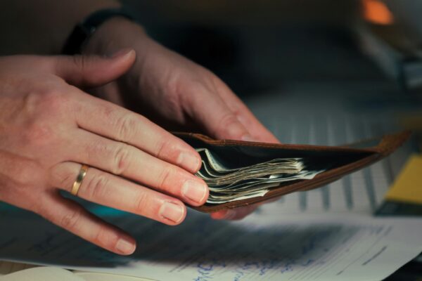 Hands holding cash in a wallet over papers.