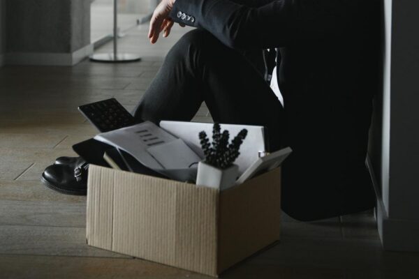 Sad fired businessman sitting outside meeting room after being dismissed
