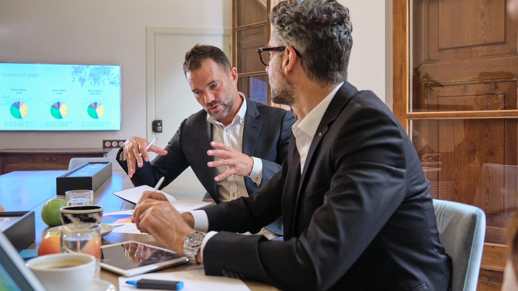 Focused businessmen sitting and having conversation about project while collaborating in office