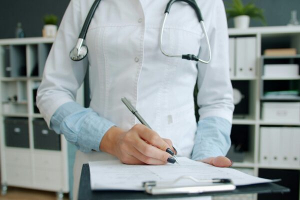 Doctor writing on clipboard in office