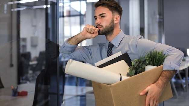 Sad dismissed worker is taking his office supplies with him from office.
