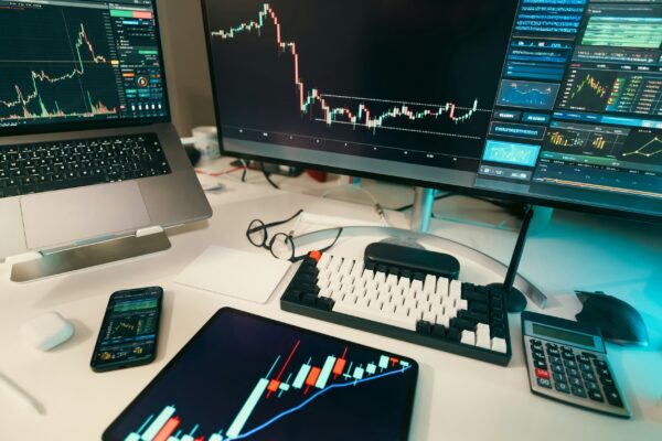 Stock charts are displayed on multiple screens.