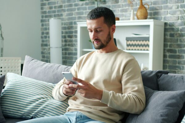 Man sitting on sofa using smartphone