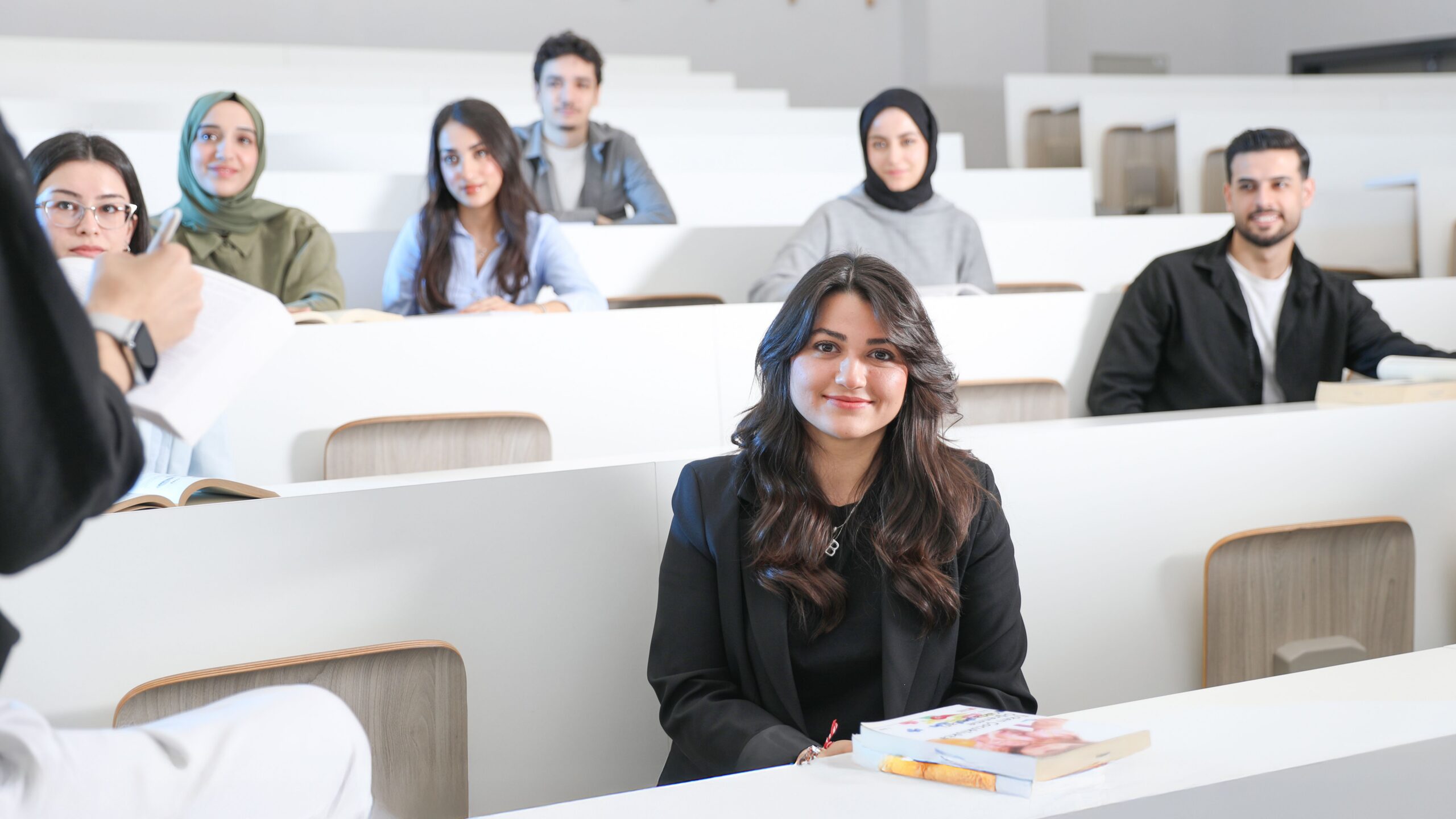 Students listening attentively in a bright university lecture hall.