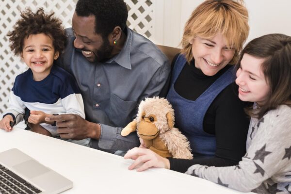 Happy mixed race family, african father, caucasian mother, using computer to make video call in quarantine, modern family using watch multimedia content and surf the internet