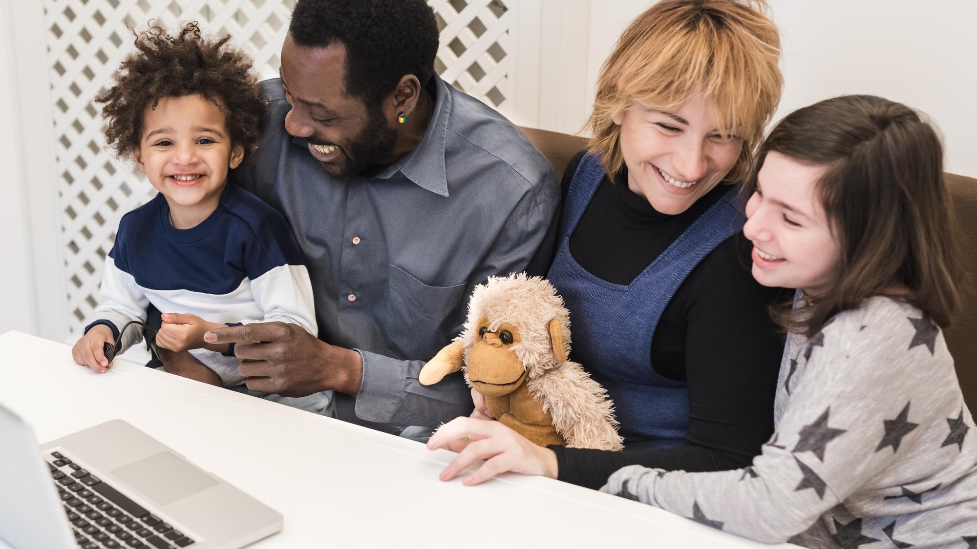 Happy mixed race family, african father, caucasian mother, using computer to make video call in quarantine, modern family using watch multimedia content and surf the internet