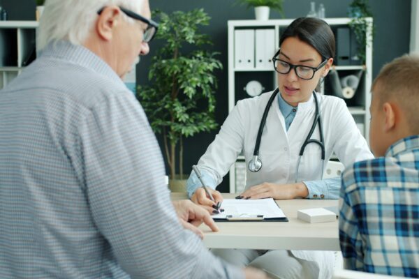 Doctor consulting with elderly man and child.