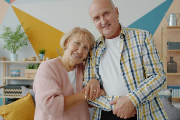 Elderly couple smiling together in a colorful room.