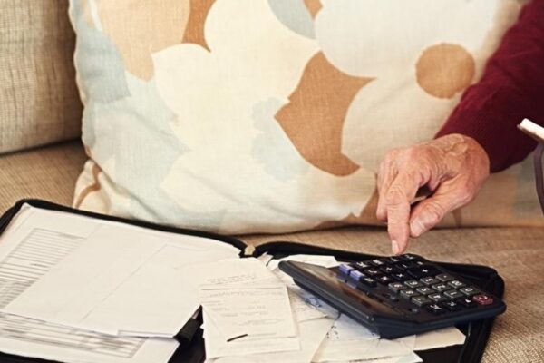 Senior man notebook and calculator on sofa for budget planning and savings account for retirement Elderly person bills and couch in lounge for mortgage personal debt and loan repayment ay home