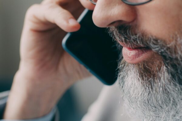 A man with a beard talking on a cell phone