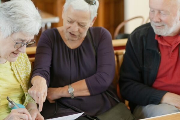 Three older adults are looking at a paper.