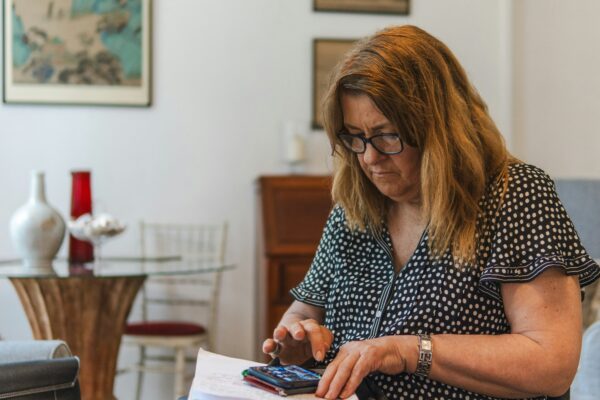 Woman using calculator with papers on table.