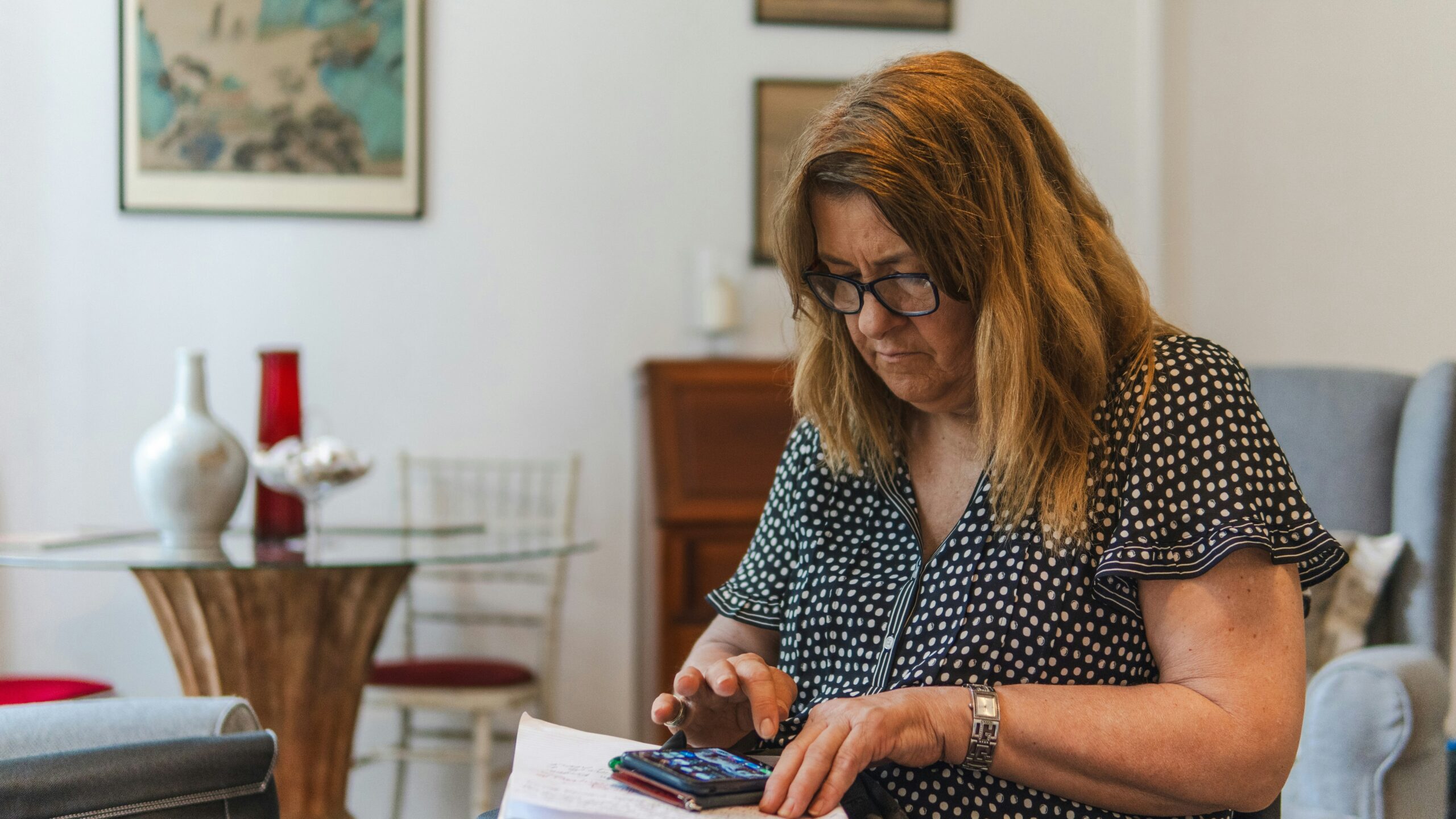 Woman using calculator with papers on table.