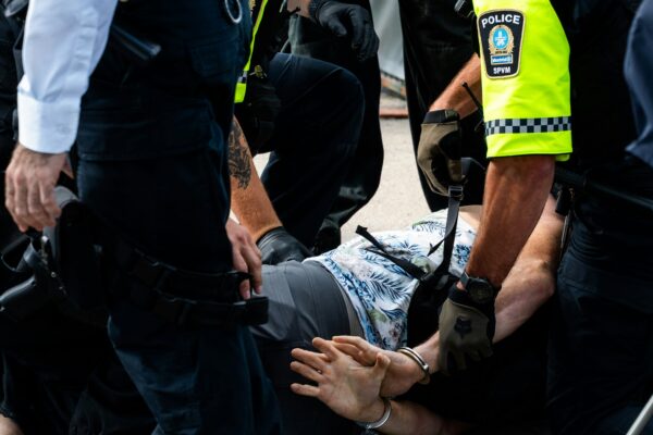 Police officers arresting a man on the ground.