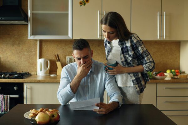 Couple looking stressed over bills at kitchen table.