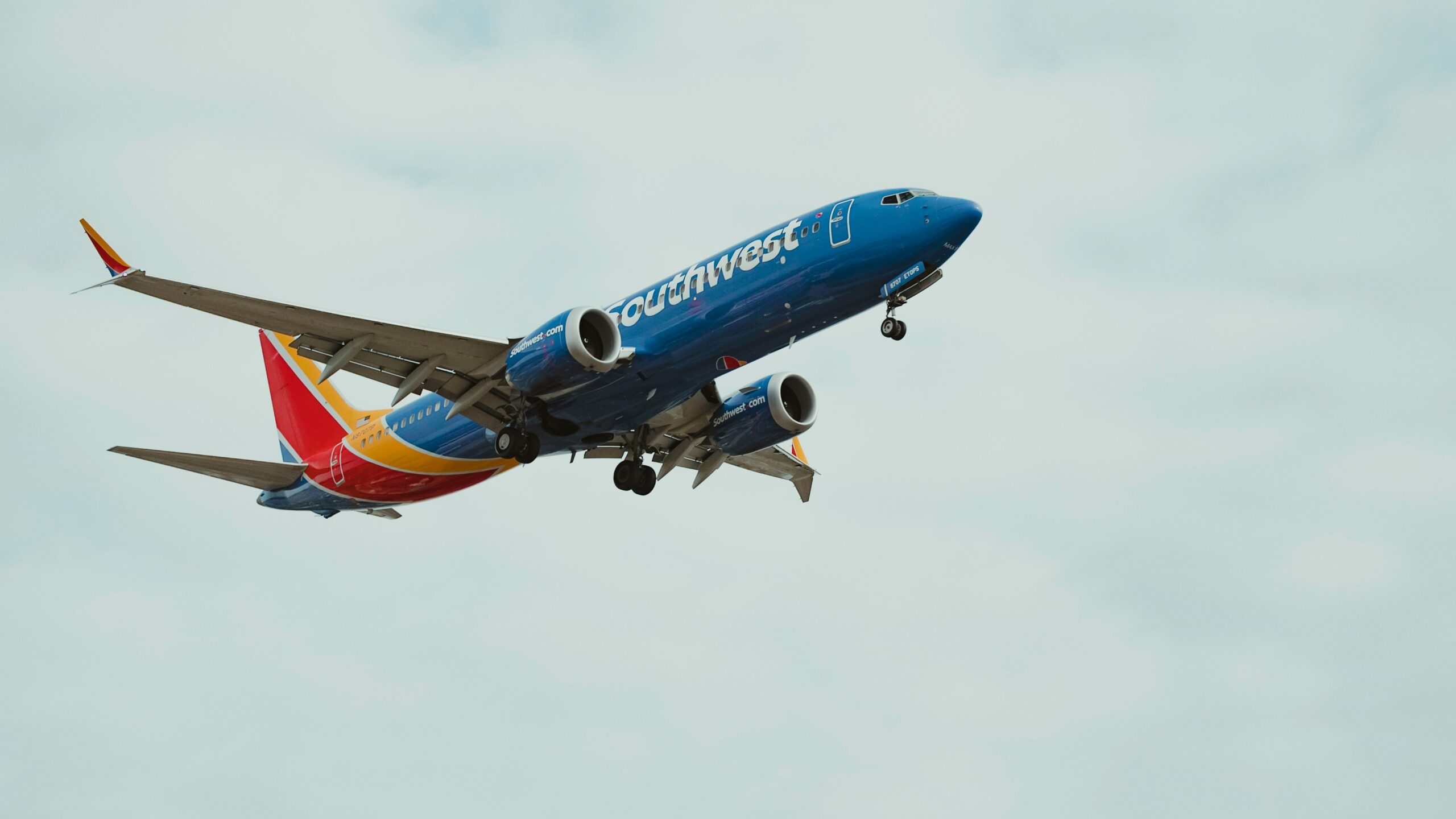 a blue and red airplane flying in the sky