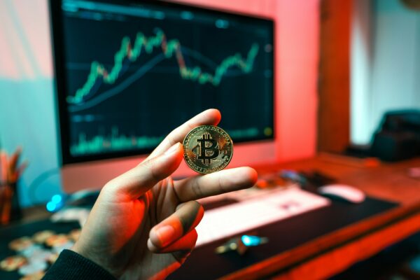 a person holding a coin in front of a computer