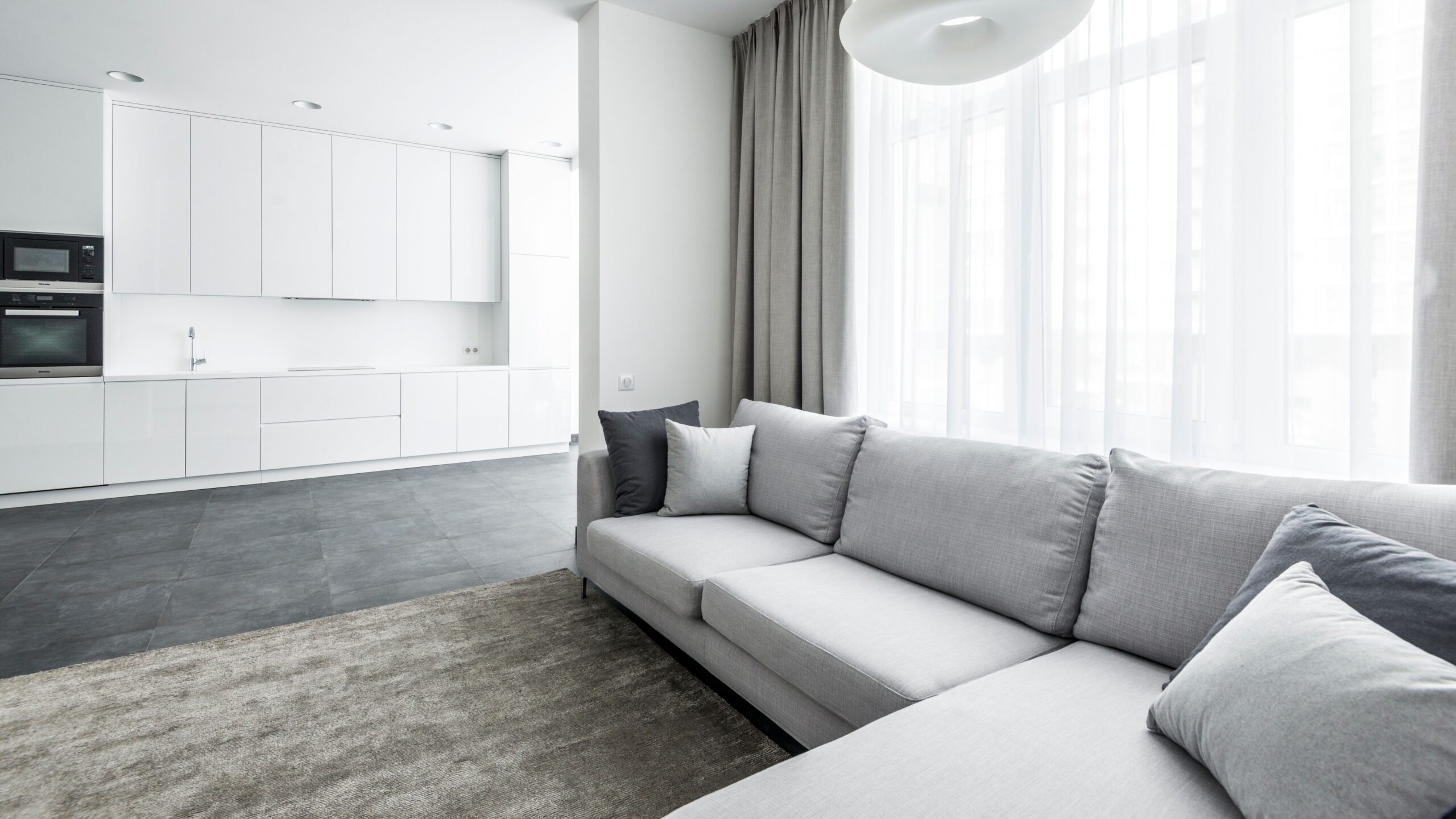 Bright modern living area featuring a cozy sofa and minimalist kitchen background.