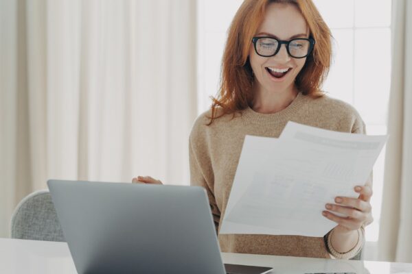 Happy excited redhead woman reading paper letter with notification about last mortgage payment