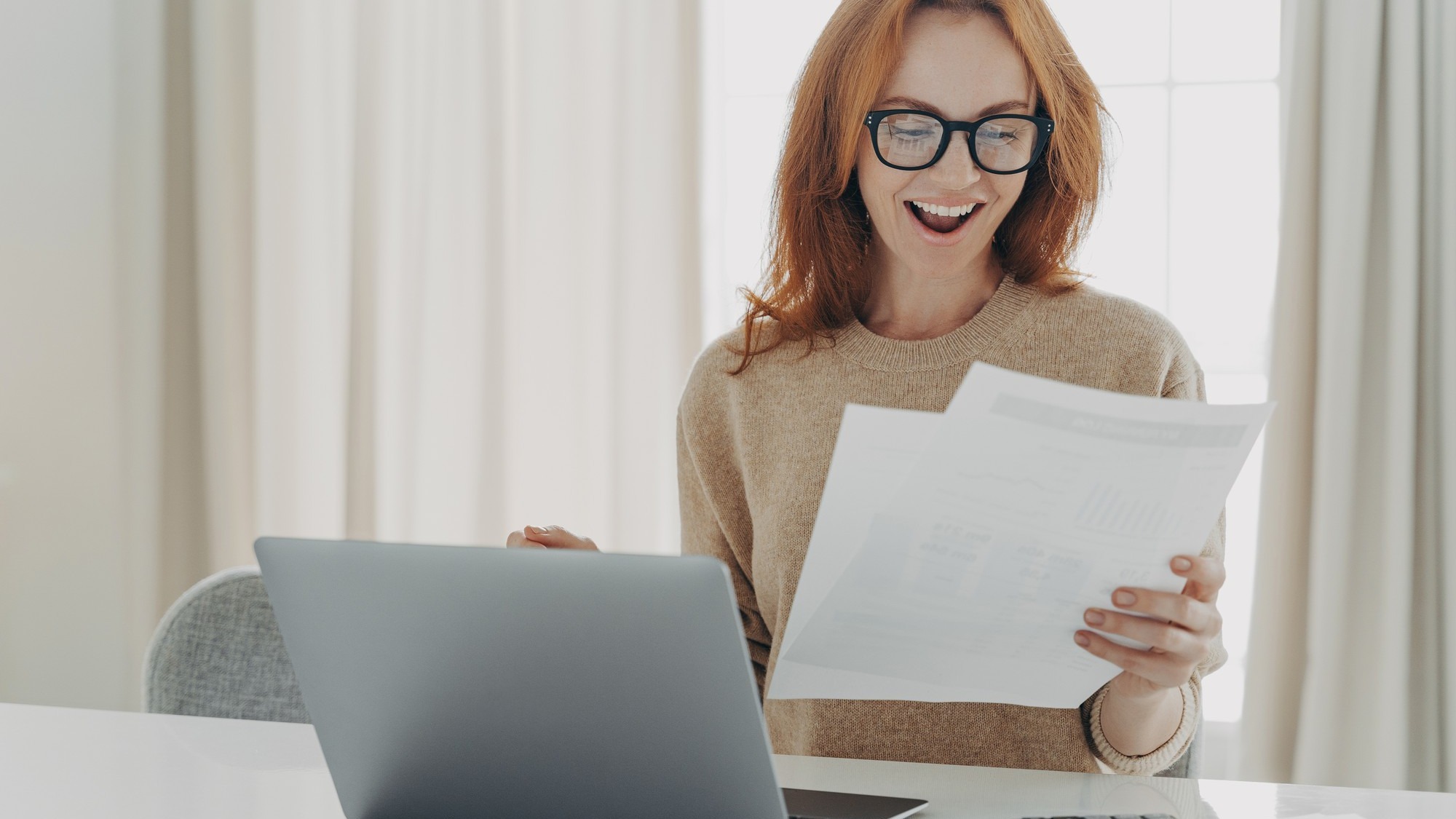 Happy excited redhead woman reading paper letter with notification about last mortgage payment