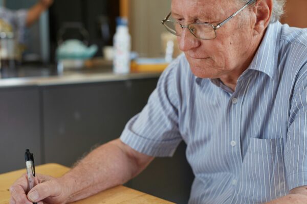 a man sitting at a table writing on a piece of paper