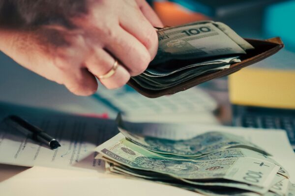 Hands counting money from a wallet over papers.