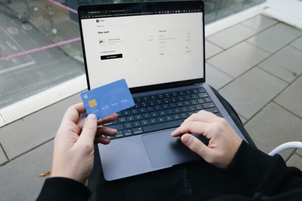 A person sitting in a chair with a laptop and a credit card