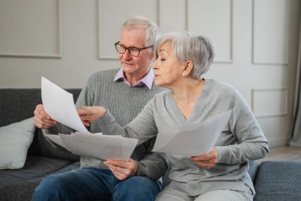 Sad tired disappointed middle aged senior couple sit with paper document unhappy older mature man