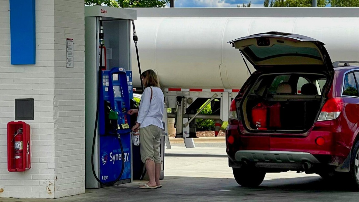man in white t-shirt standing beside red suv during daytime