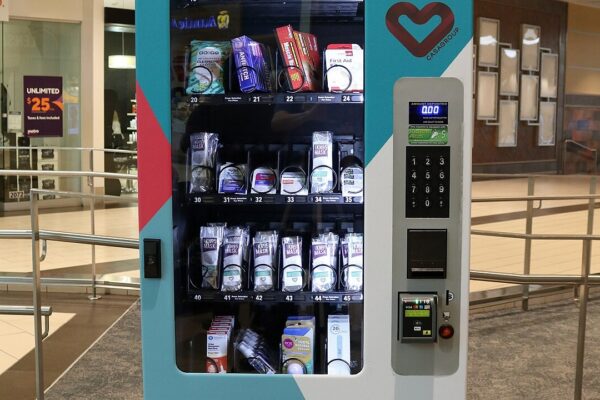 Front view of a CasaGroup (Casa Group) Pharmachine vending machine in the Westfield Countryside shopping mall in Clearwater, Florida. Items visible from inside the machine include toothbrushes and toothpaste; anti-itch cream; Assured muscle rub gel; Carepak travel-size first aid kits; KN95 face masks; NyQuil, Benadryl, Motrin, and Advil products; decongestant nasal sprays; A Gift From Nature hand sanitizer; EOS lip balm; and thermometers.