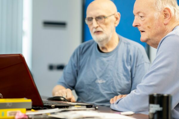 two men sitting at a table looking at a laptop