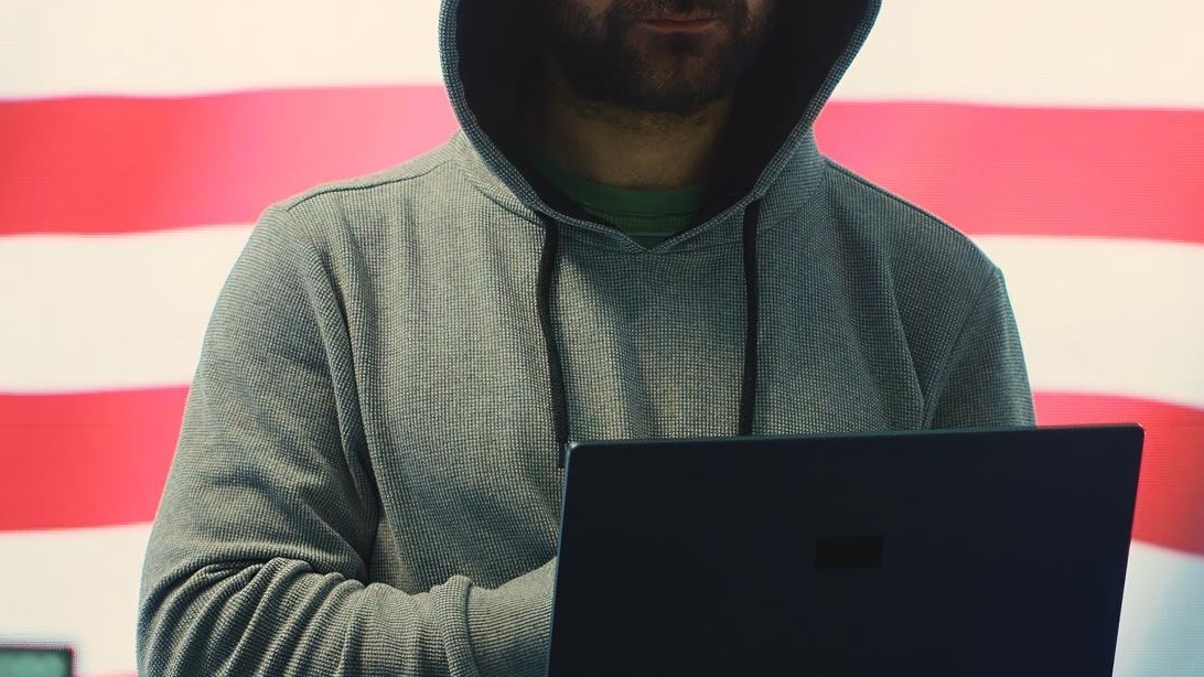 A hacker working in a governmental IT workspace with the USA flag