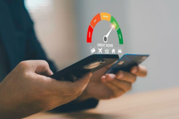 Businessman holding credit card and smartphone with credit score gauge showing good rating for financial health personal finance credit analysis responsible spending and banking technology concept