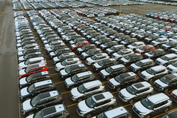 Aerial shot of an extensive car parking lot filled with new vehicles ready for distribution.