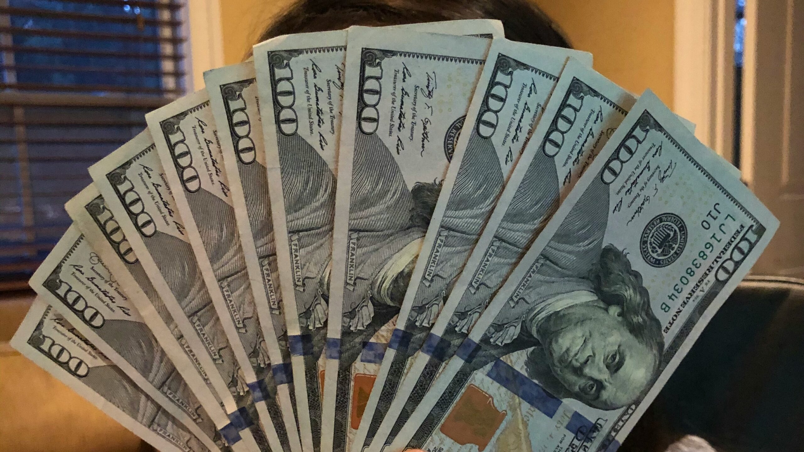person holding fan of us dollar bill