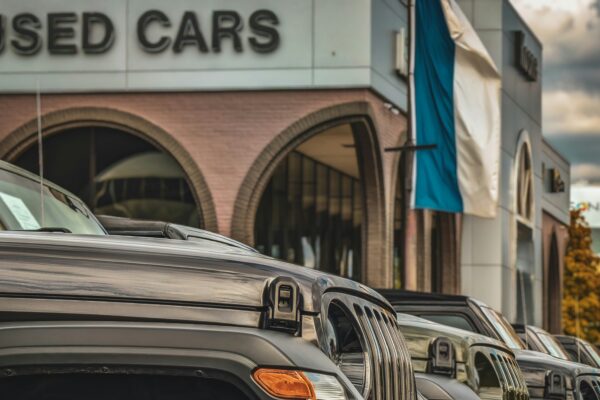 a row of parked cars in front of a used car store
