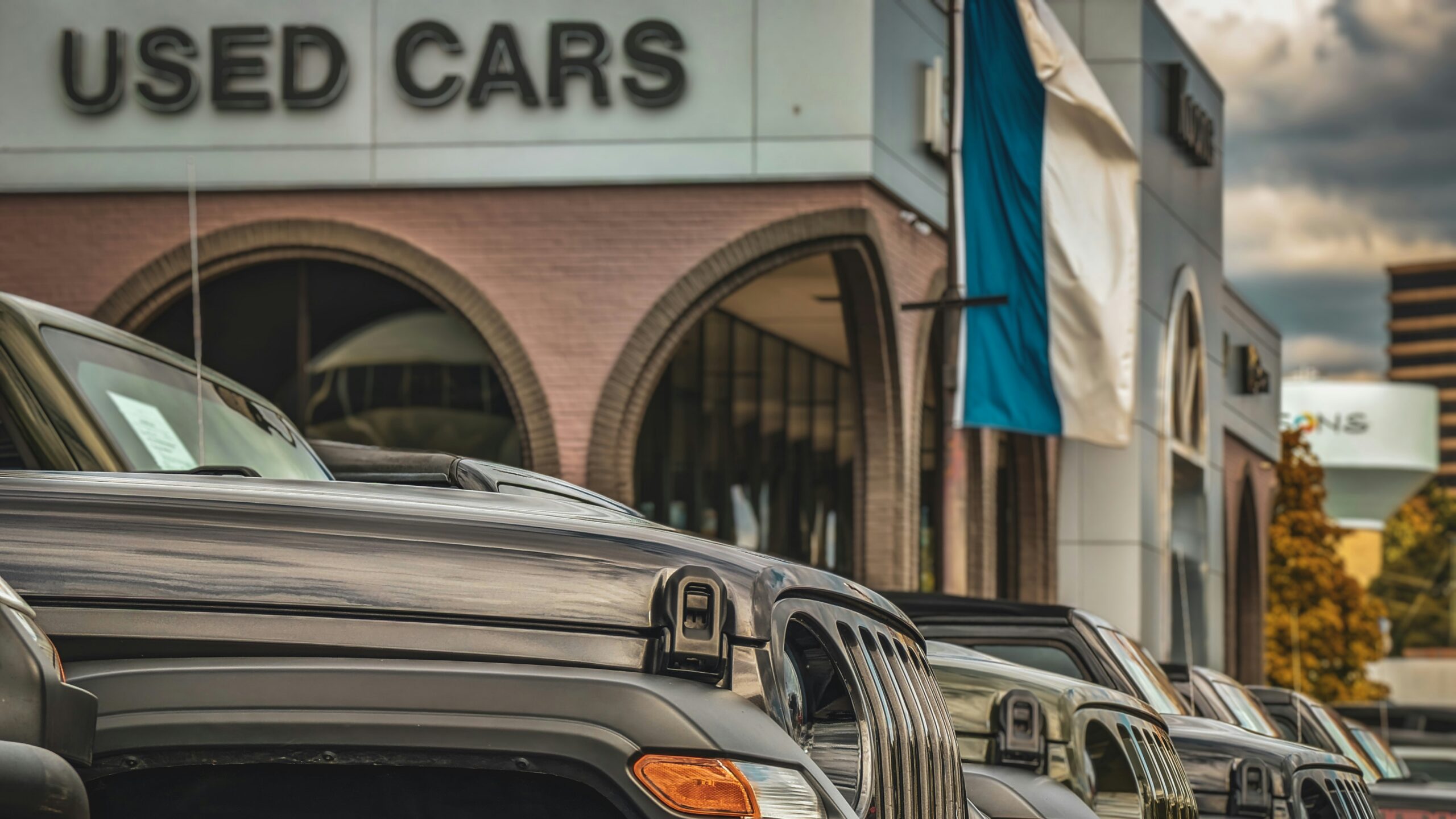 a row of parked cars in front of a used car store