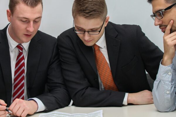 four men looking to the paper on table