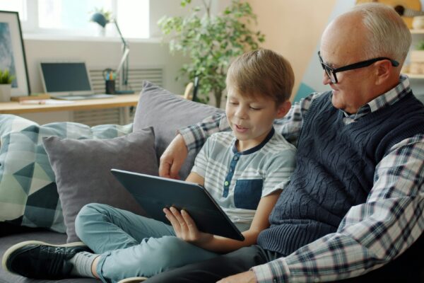 Grandfather and grandson looking at a tablet together.
